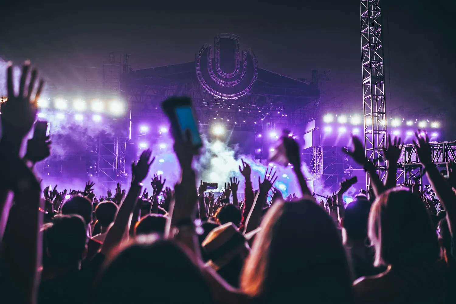 A crowd with raised hands under stage lights