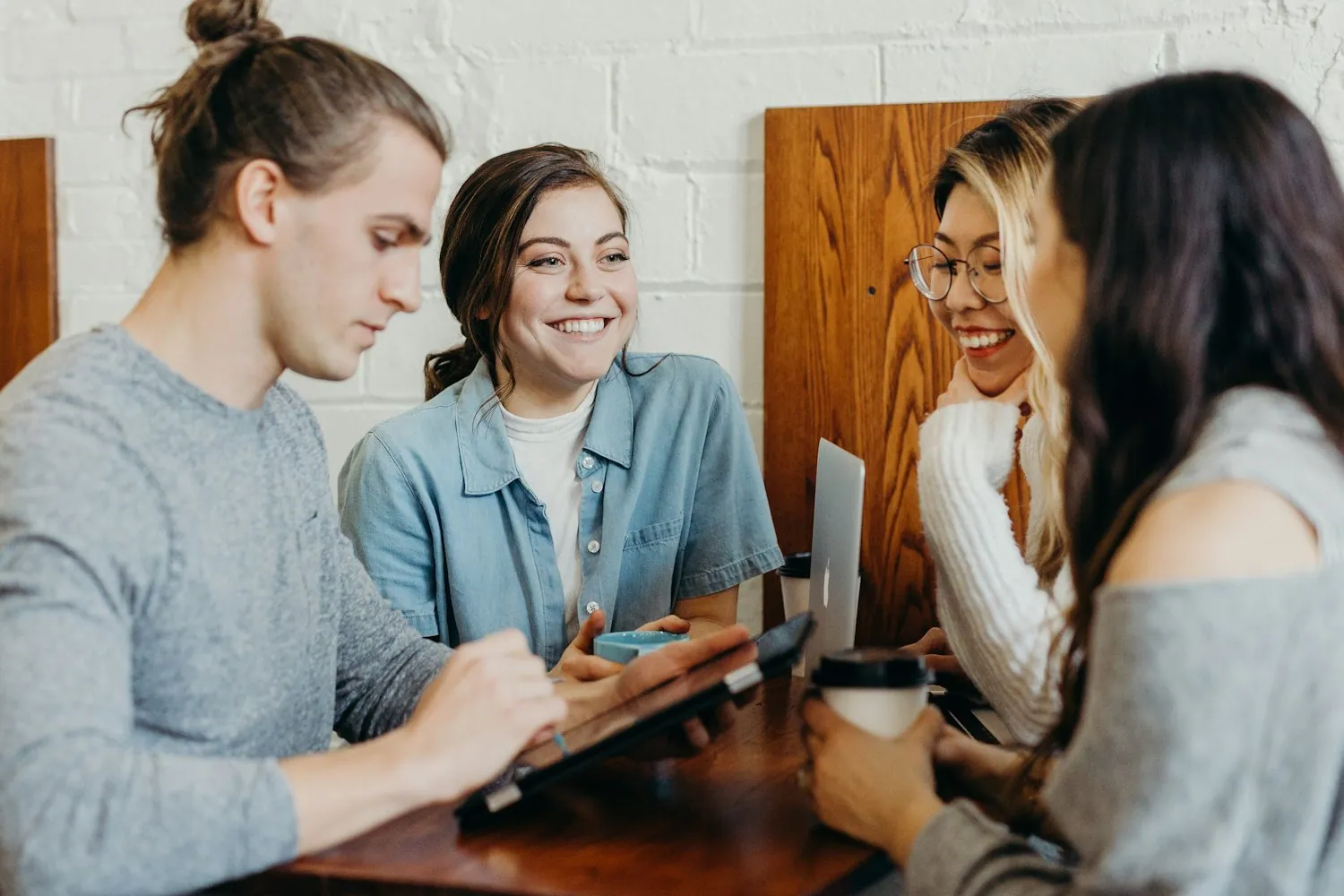 Three friends laughing together around a table at a gathering