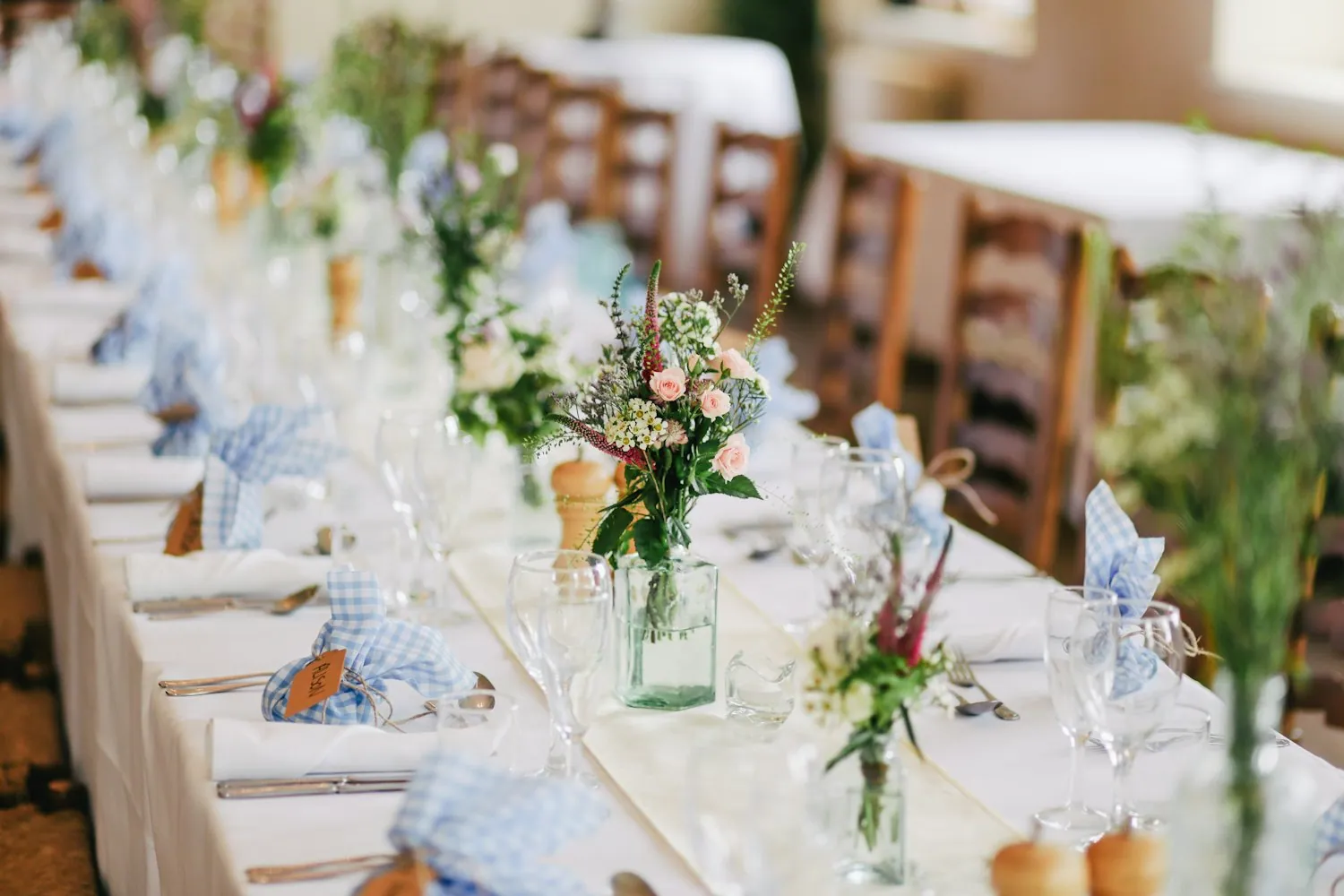 Outdoor reception tables set with flowers and glassware